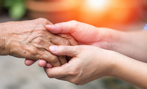 Young person holding an elder persons hand during elder abuse month